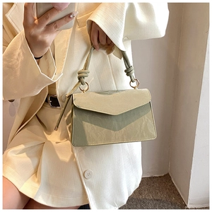 Detail of light green textured handbag with knotted strap and envelope flap closure
