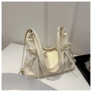 Detail view of cream tote bag featuring stylish bow knots and silver zipper accents