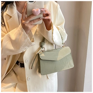 Détail d'un petit sac bandoulière vert clair porté sur un blazer beige élégant