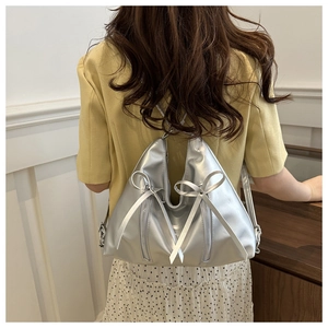 Detail of silver metallic tote bag with decorative silk bows and dual zippers on back