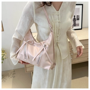 Dettaglio borsa tote rosa chiaro con fiocchi e cerniere metalliche indossata a spalla