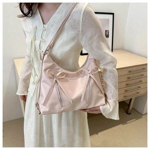 Detail of light pink bucket tote bag with decorative double bows and vertical zippers
