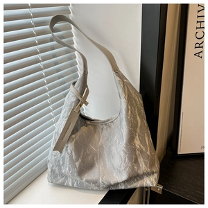 Détail d'un sac hobo argenté avec texture plissée et étiquette de mode stylée