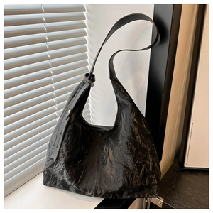 Détail d'un sac cabas plissé noir avec étiquette mode et bandoulière élégante