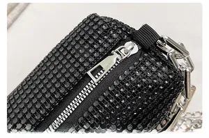 Close-up of black rhinestone mini bag with silver chain strap and metal zipper detail