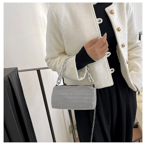 Silver rhinestone cylinder bag with metallic chain straps shown on a stylish model