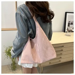Grand sac cabas plissé rose porté avec une veste en jean dans un intérieur chaleureux