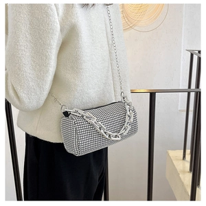 Detail of silver rhinestone cylinder crossbody bag with chunky metal chain on model