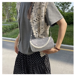 Détail du sac à main argenté avec strass brillants et bandoulière en perles nacrées