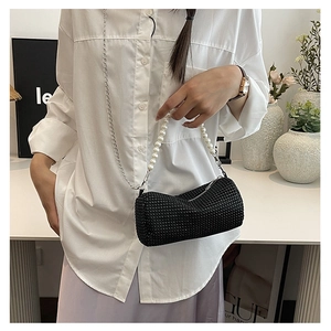 Détail d'un sac à main noir en strass avec poignée en perles et chaîne sur un mannequin