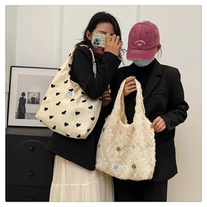 Detail of beige textured heart tote bag and white floral faux fur shoulder bag