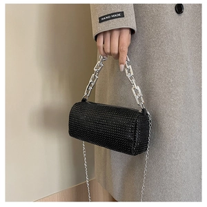 Detail of a black rhinestone cylinder bag with silver chain handle and metallic hardware