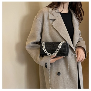 Detail of a black rhinestone cylinder evening bag with silver chain handle for women