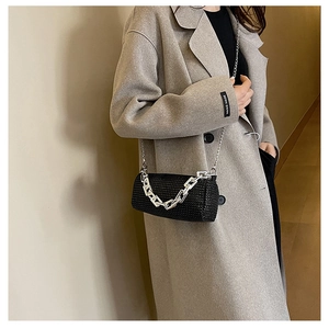 Detail of black rhinestone cylinder bag featuring dual silver metal chains on shoulder