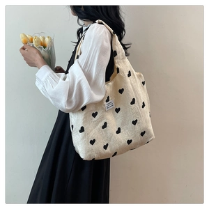 Detail of cream canvas tote bag with black heart pattern and fashion woven label