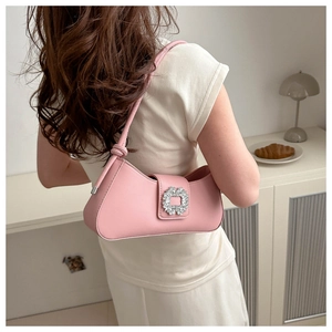 Detail of pink baguette shoulder bag with a square rhinestone buckle on model's shoulder