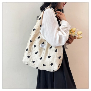Close-up of a cream tote bag featuring a black heart pattern and a Fashion fabric label