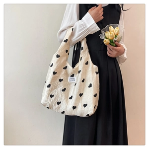 Detail of off-white heart pattern tote bag with pleated texture and fashion label