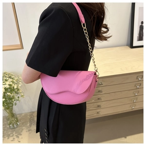 Detail of pink saddle bag with wavy edge flap and gold chain strap on shoulder