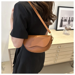 Détail du sac selle en cuir marron mat avec boucle en métal doré et bandoulière réglable