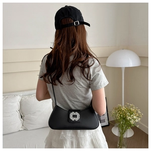 Detail of black underarm bag with sparkling silver rhinestone buckle on smooth leather