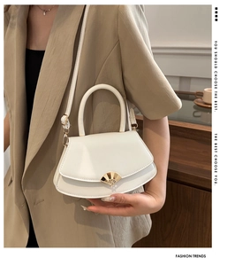 Détail du sac à main en cuir blanc avec boucle dorée en forme d'éventail sur blazer