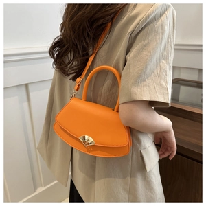 Détail d'un sac orange vif avec un élégant fermoir métallique doré en forme d'éventail