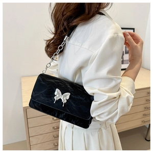 Detail of black pleated velvet crossbody bag with silver butterfly and chain strap