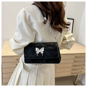 Detail of black pleated shoulder bag with silver butterfly metal buckle and chain strap