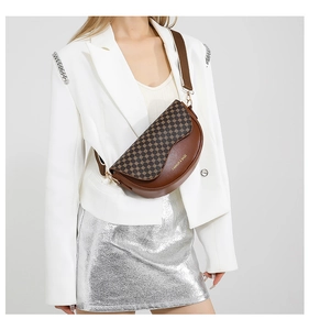 Close-up of a brown leather saddle bag with vintage monogram and stylish wide strap