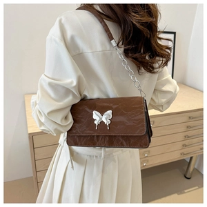 Macro detail of dark brown pleated leather bag with silver metal butterfly decoration