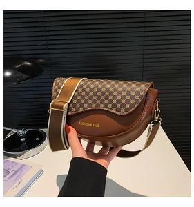 Detail of a brown saddle bag with geometric patterns and a wide jacquard strap