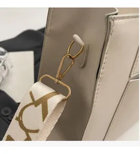 Détail de mousquetons dorés et bandoulière à motifs sur un sac à main crème chic