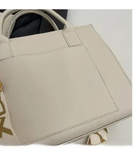 Gros plan du sac cabas en cuir crème avec une large bandoulière à motif géométrique