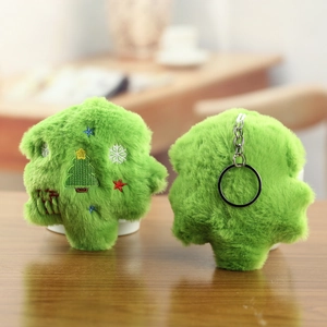 Detail of plush Christmas tree keychains with festive embroidery on a wooden surface