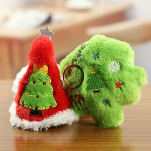 Close-up of plush Christmas tree and hat keychains with festive embroidery on wood