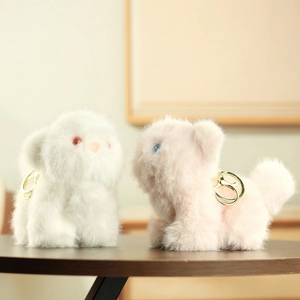 Close-up of cute plush cat keychains in white and pink with fluffy texture and gold metal rings