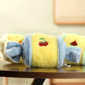 Close-up of yellow and blue plush candy pendant with cherry embroidery detail
