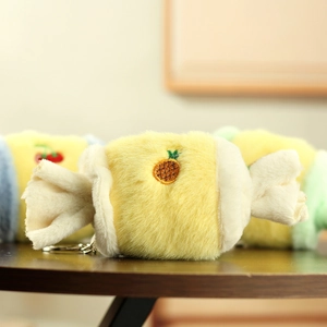 Detail of plush candy-shaped keychain with pineapple embroidery and soft faux fur texture
