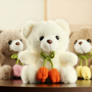 Close-up of soft plush bear charms with handmade knitted tulip pendants on wooden desk