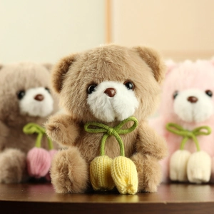 Detail of plush brown teddy bear with green ribbon and yellow tulip pendant