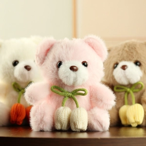 Detail of cute plush teddy bears with green bows and knitted tulip charms for bags