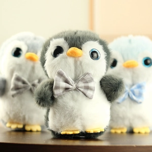 Gros plan de pendentifs pingouins en peluche avec yeux bleus et nœuds papillons mignons