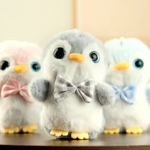 Détail de trois porte-clés pingouins en peluche douce, coloris gris, rose et bleu avec nœuds