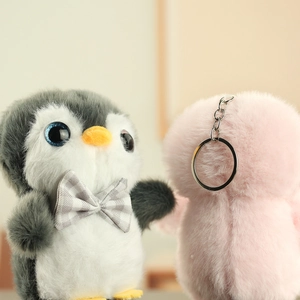 Gros plan de porte-clés pingouins en peluche gris et rose avec fourrure douce et clips
