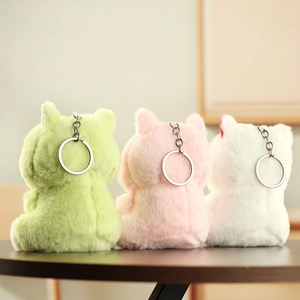Vista posteriore di portachiavi a gatto in peluche verde, rosa e bianco su legno