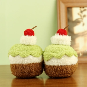 Detalle de dos llaveros de cupcake de peluche con cereza en una mesa de madera