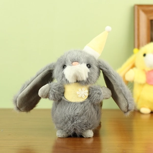 Close-up of grey plush bunny with yellow daisy bib on wooden desk with green background