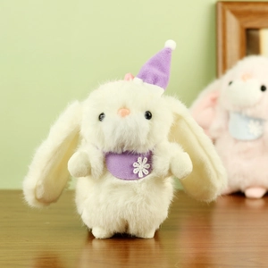Detail of white plush bunny with purple pom-pom hat and snowflake scarf on wood desk