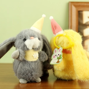 Close-up of grey and yellow plush bunnies with party hats on a wooden surface